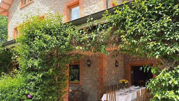 An outdoor dining area with a brick wall, a table set for four, and a pergola covered with greenery. - Villa Las tres Mares 6826 (Noja)