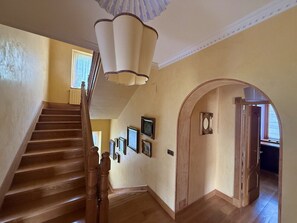 A staircase with wooden railings, a chandelier, and framed pictures on the wall. - Villa Las tres Mares 6826 (Noja)