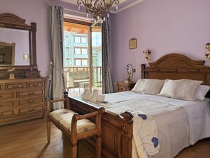 A bedroom with a wooden bed, a dresser, a chair, and a large window with curtains. - Villa Las tres Mares 6826 (Noja)