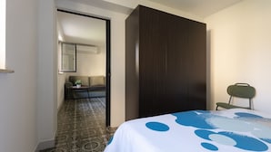 Ein Schlafzimmer mit Bett, Kleiderschrank, Stuhl und einem Tisch mit Pflanze.