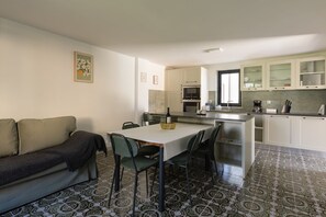 A compact living space with a sofa, a dining table with chairs, a kitchen area with cabinets and appliances, and patterned floor tiles. - Apartment Stephanie with terrace for 2 person (Pula)