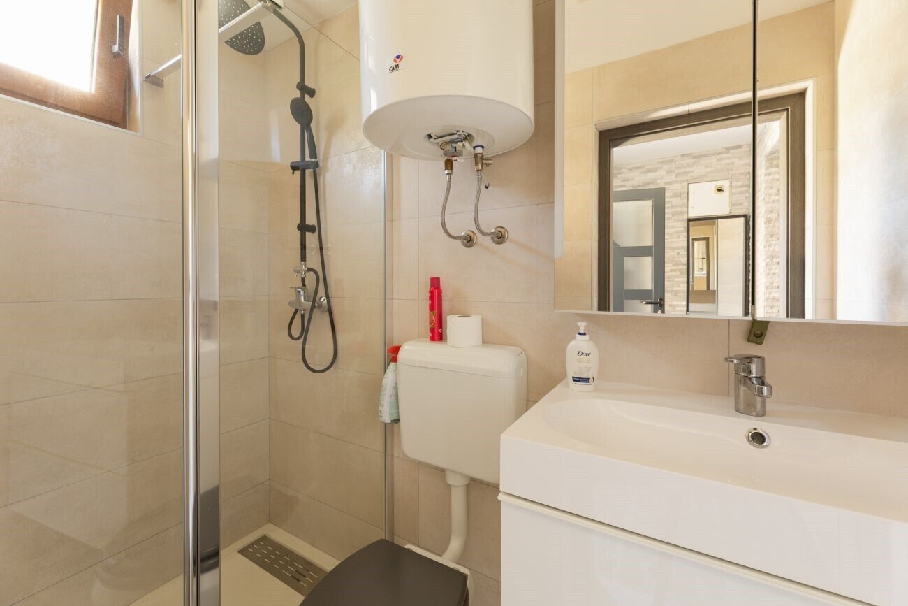 Une salle de bain moderne avec une douche à parois de verre, un lavabo blanc et des toilettes.