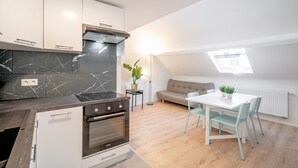 Eine moderne Küche mit integrierten Geräten, ein Essbereich mit Tisch und Stühlen, eine Couch und ein Oberlicht.