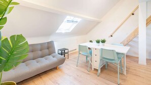 Ein Loft-Zimmer mit Sofa, Esstisch, Stühlen und einem Oberlicht.