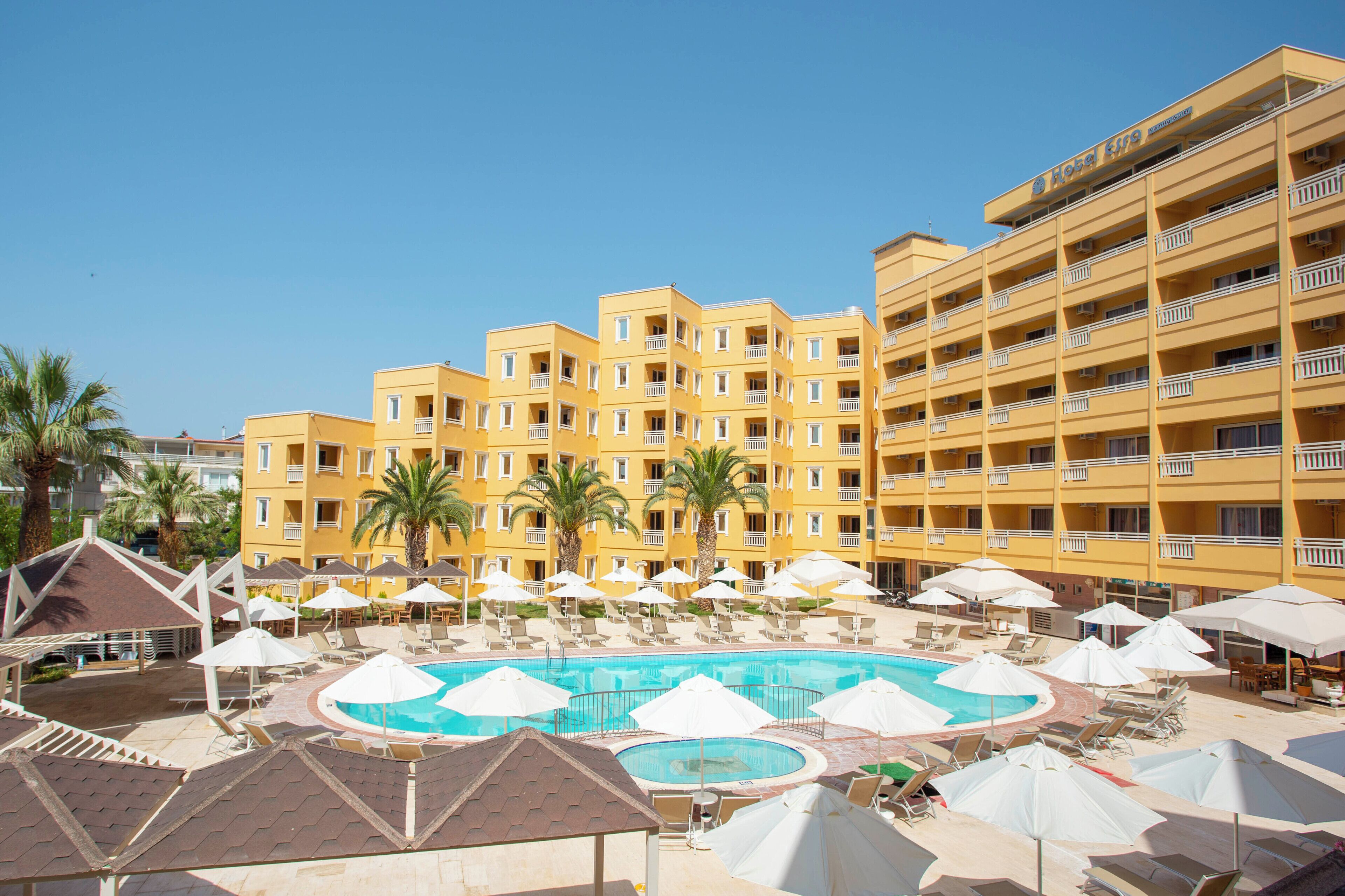 A hotel with a pool area, multiple balconies, and palm trees.