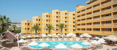 A hotel with a pool area, multiple balconies, and palm trees.