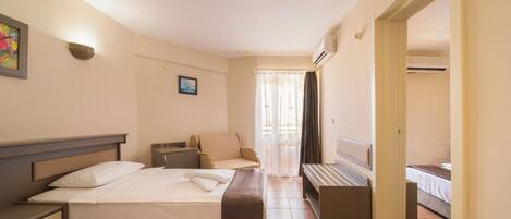 A hotel room with two beds, a sofa, a desk, and a window with curtains.