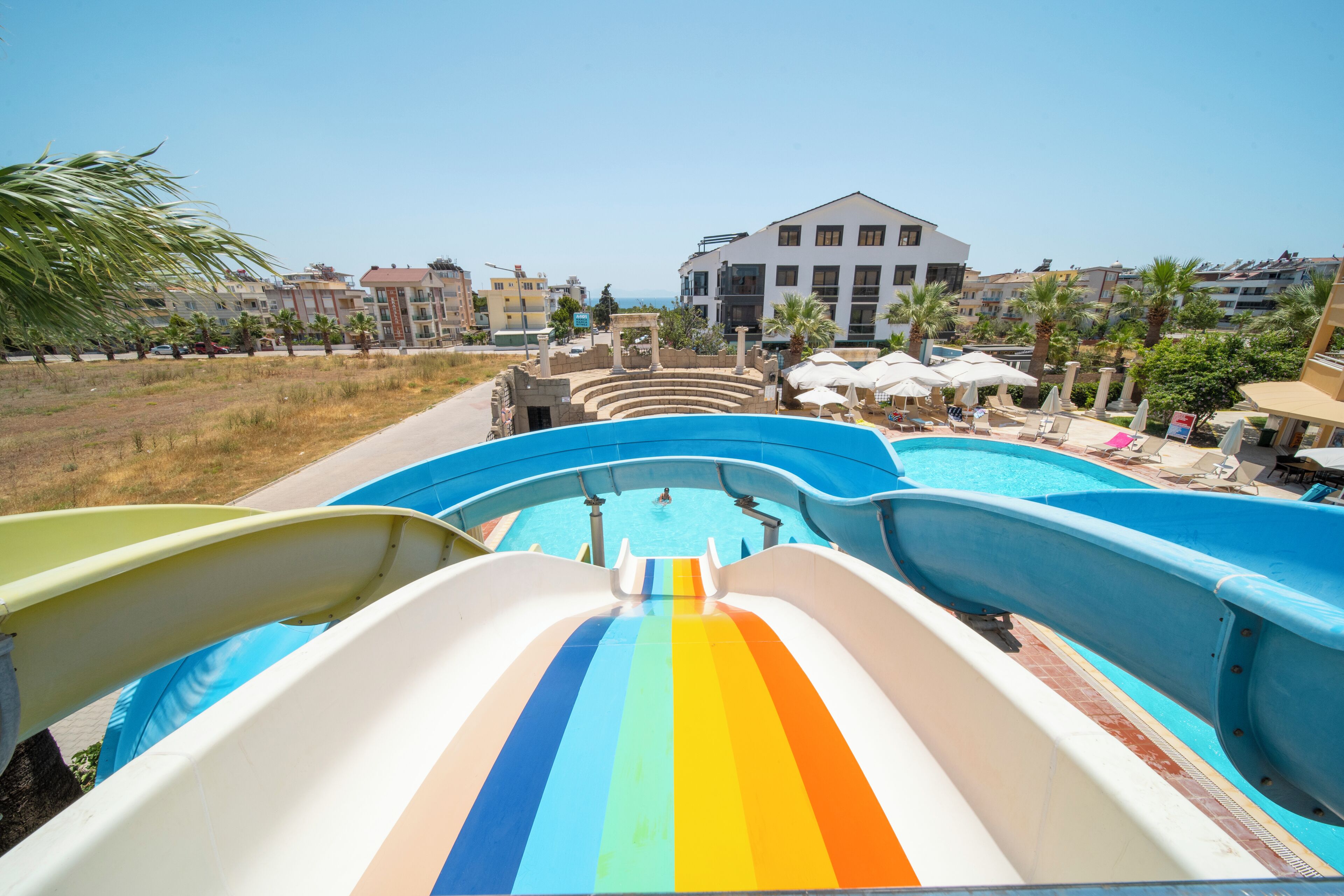 Tobogán de agua que lleva a un área de piscina con vistas a un edificio de resort.