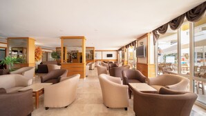 A hotel lobby with multiple seating areas, a reception desk, and large windows offering views of the outside. - Hotel Esra Family Suite - All inclusive (Didim)