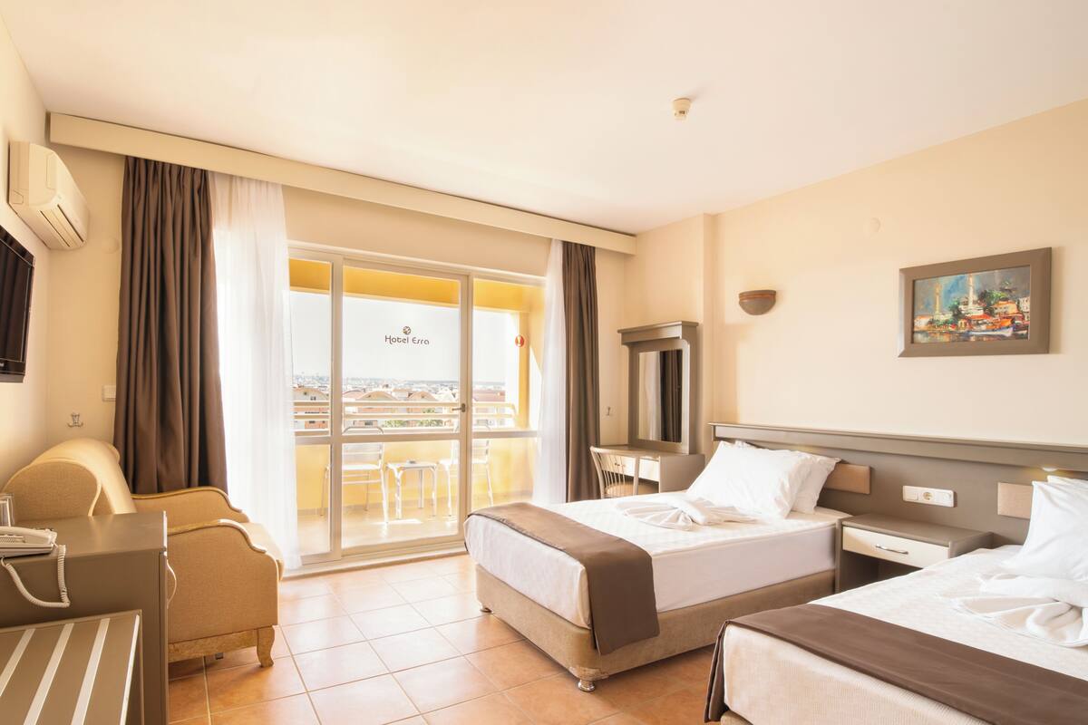 Une chambre d’hôtel avec deux lits, un bureau, une chaise et un balcon avec vue.