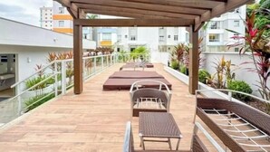 A covered outdoor patio with wooden flooring, seating areas, and potted plants.