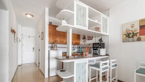 Een kleine keuken met witte kastjes, een aanrecht en een magnetron.