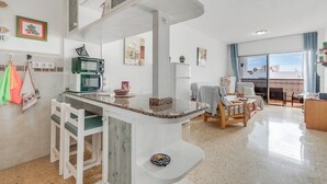Een moderne keuken met een magnetron, een koffiezetapparaat en een eethoek met een stoel en tafel.