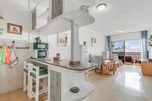 Eine moderne Küche mit Mikrowelle, Kaffeemaschine und Essbereich mit Stuhl und Tisch.
