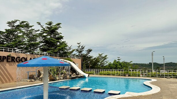 A swimming pool with a water slide, steps leading into the pool, and a sign in the background. - Beautiful 5-BR House with AC in Zaragoza. Community Pool & Close to the Beach! (Zaragoza)