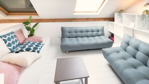 Uma sala de estar no estilo loft com um claraboia, um sofá, uma mesa de centro e uma estante.
