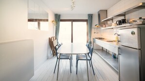 Uma cozinha moderna com mesa e cadeiras, eletrodomésticos de aço inoxidável e uma janela grande com cortinas.