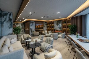 A modern lounge area with sofas, armchairs, a dining table, and a fireplace.