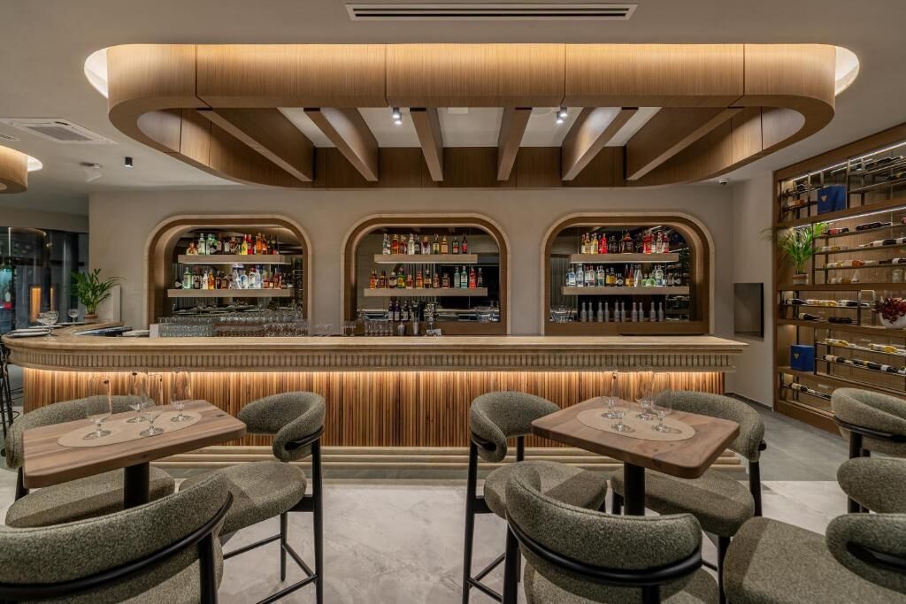 A bar area with a counter, shelves of bottles, and seating.