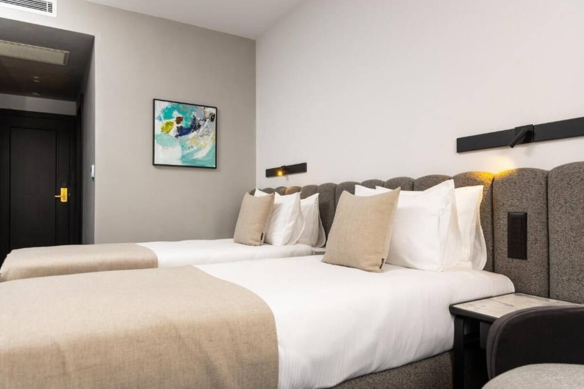 Ein Hotelzimmer mit zwei Betten, einem Bild an der Wand und einem kleinen Tisch.