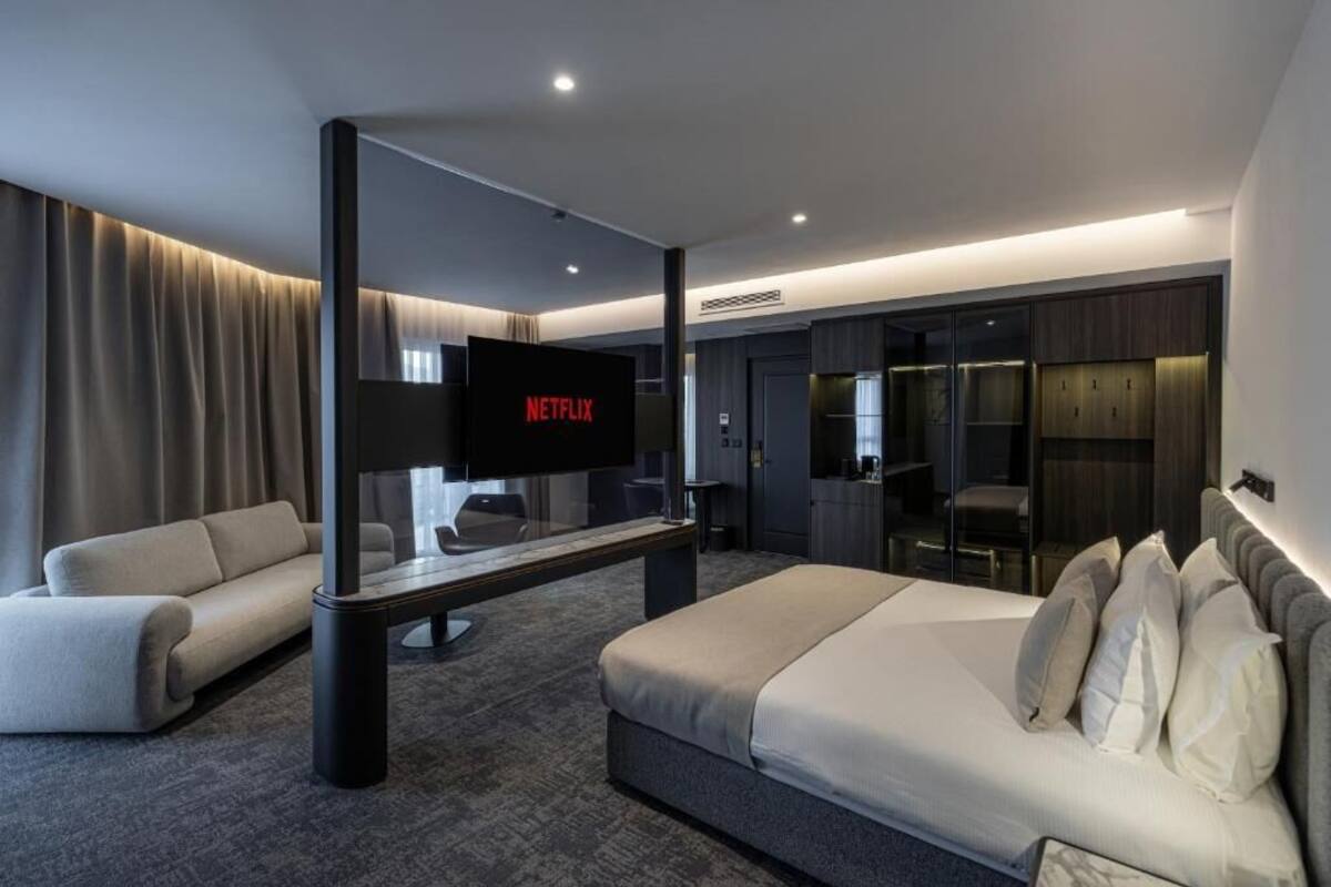 Ein modernes Hotelzimmer mit einem großen Bett, einer Couch, einem Flachbildfernseher und einer Minibar.