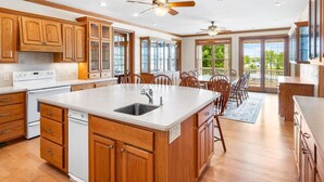 A spacious kitchen with wooden cabinets, a central island, and a dining area with chairs. - Expansive Luxury at The Waterfront on Green Lake (Green Lake)