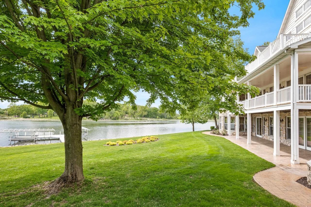 A building with a covered porch and a large tree in front.