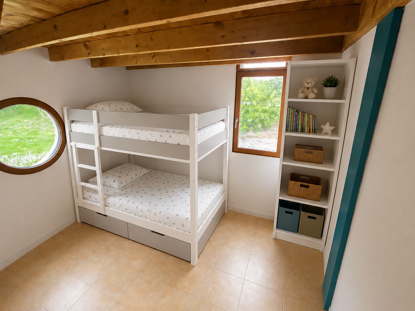 A bunk bed with storage drawers, a small window with a view of greenery, and a bookshelf with books and baskets.