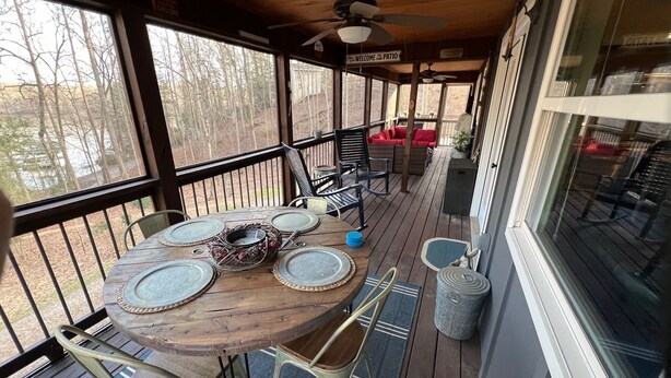 Un patio exterior techado con una mesa redonda de madera dispuesta para cuatro personas, rodeado de sillas de metal.