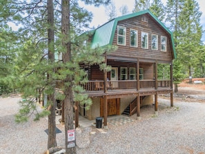 A cabin with a wooden exterior, a balcony, and a gravel driveway. - Treetop Lodge | 3 bdrm Duck Creek Cabin (Duck Creek Village)