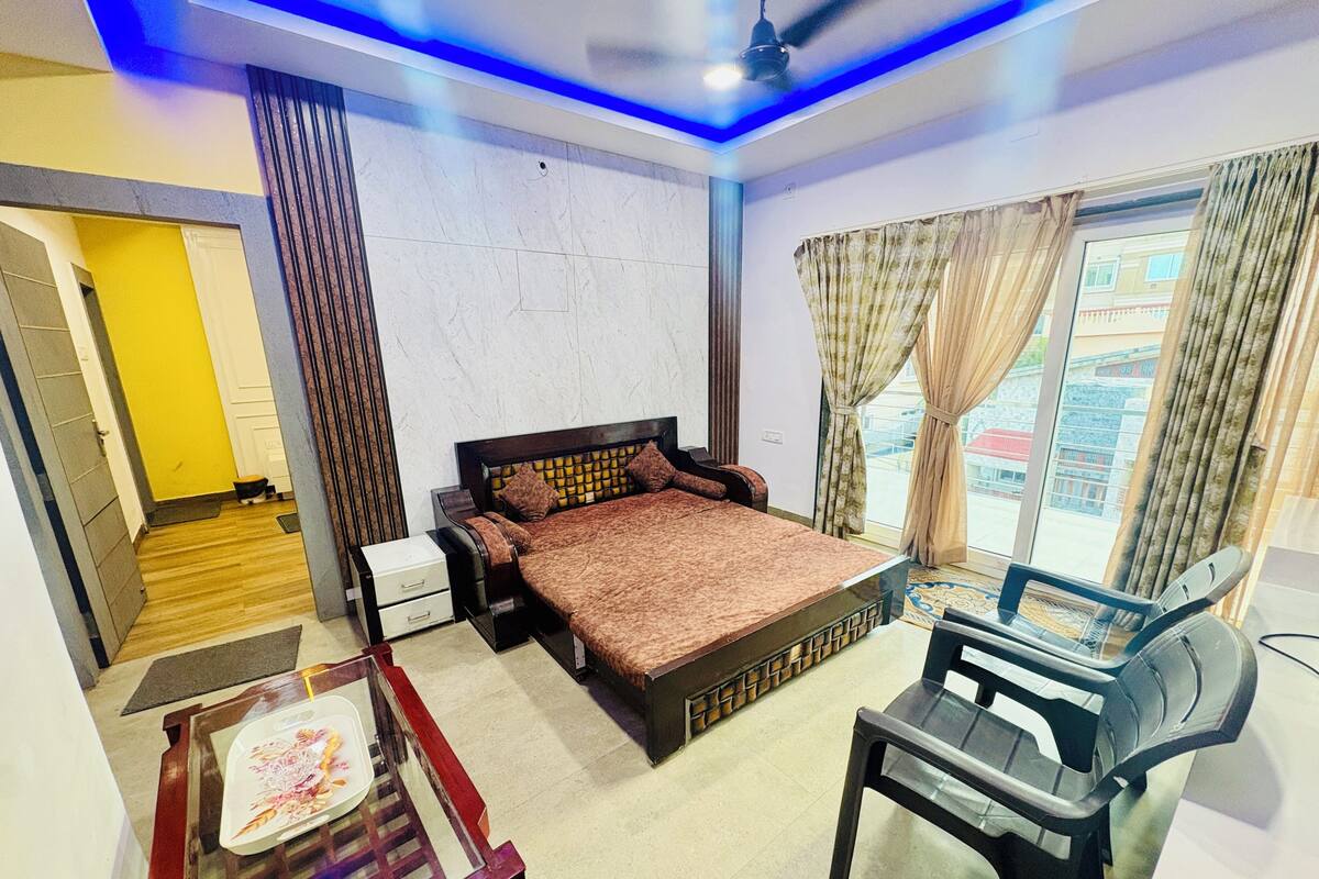 A bedroom with a bed, a desk with a chair, a window with curtains, and a ceiling fan.
