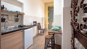 A compact kitchen with a sink, microwave, and a small dining area with stools.