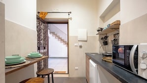 A compact kitchen with a microwave, a sink, and a small dining area with stools.