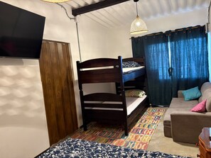 A bunk bed with a TV mounted on the wall, a hanging light fixture, a sofa with cushions, and a patterned rug. - Apartment in the Historic District of Santa Marta (santa marta magadalena)
