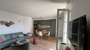 Uma sala de estar moderna com um sofá cinzento, uma mesa de centro redonda e um suporte para TV.