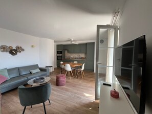 Ein modernes Wohnzimmer mit einem grauen Sofa, einem runden Couchtisch und einer TV-Konsole.