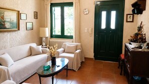 Un accogliente soggiorno con divano, tavolino, una porta verde e una finestra con tende.