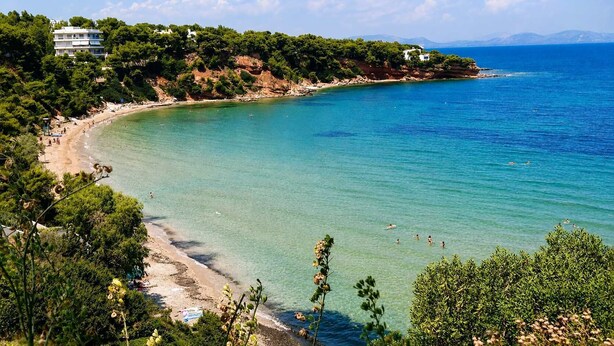 Una vista costiera con spiaggia, acqua cristallina e edifici su una collina.