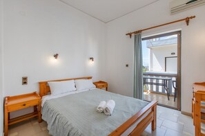Un dormitorio con cama, mesitas de noche, cortinas en la ventana y vistas al exterior.