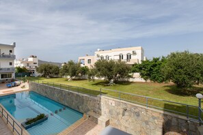 En swimmingpool med stenmurar, en gräsyta och byggnader i bakgrunden.