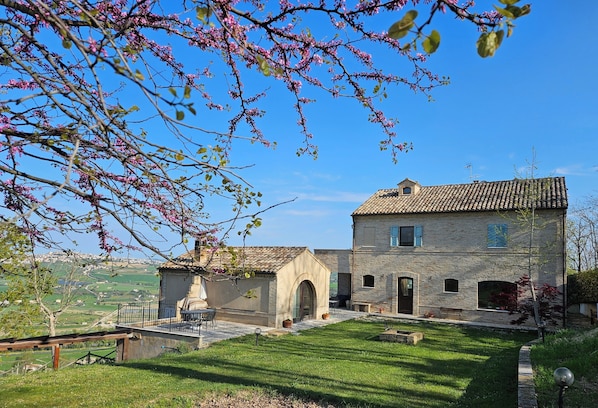 A stone building with a tiled roof, an arched doorway, and a small garden area. - Romantic 2-bedroom villa with AC in charming Fermo, Le Marche (Marche)