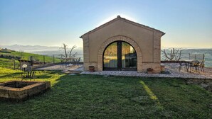 Ein Steingebäude mit Bogenportal, Außenbereich zum Sitzen und Blick auf ferne Berge.