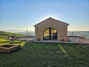 A stone structure with an arched doorway, outdoor seating, and a view of distant mountains. - Romantic 2-bedroom villa with AC in charming Fermo, Le Marche (Marche)