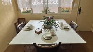 Ein Esstisch mit vier Stühlen, einer Topfpflanze und einer kleinen Tischleuchte.