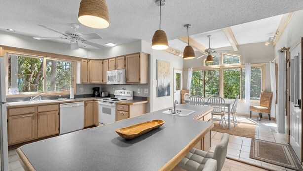 Une cuisine moderne avec des meubles en bois, un îlot central et des luminaires suspendus.
