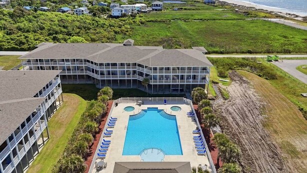 Ein Hotel mit großem Schwimmbad, mehreren Balkonen und Blick auf den Strand.