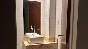 Une salle de bain avec un lavabo blanc, un miroir et un porte-serviette fixé au mur.