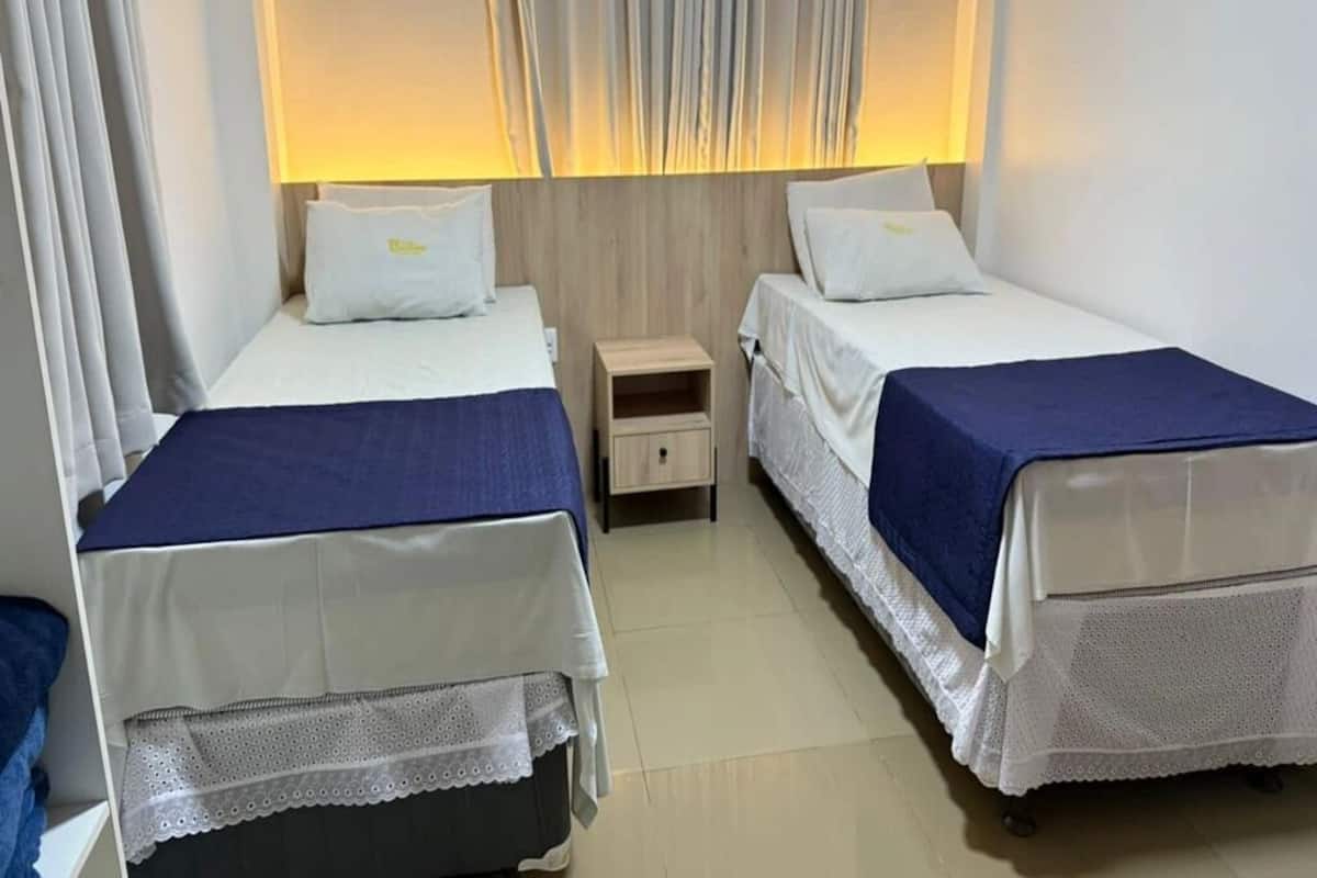 A twin room with two beds, a nightstand, and a lamp.