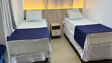 A twin room with two beds, a nightstand, and a lamp.
