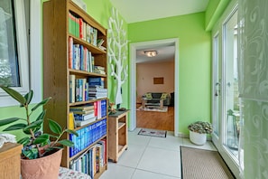 A room with a bookshelf, a potted plant, a door leading to another room, and a window.